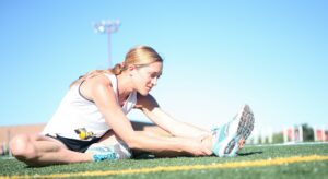 woman stretching hamstring. Potentially has a pulled hamstring and is practicing pulled hamstring exercises. to reduce hamstring pull recovery times