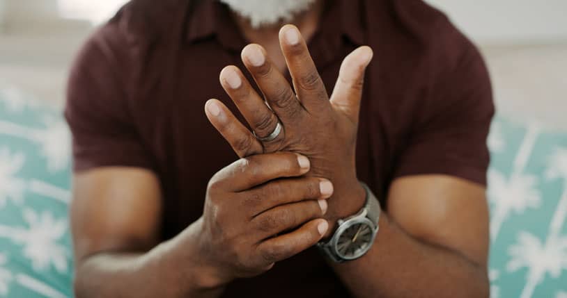 Man sitting alone on his sofa at home and suffering from arthritis types in his hand