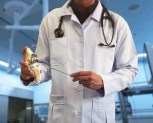 Doctor holding up a model of a knee joint explaining meniscus repair procedures
