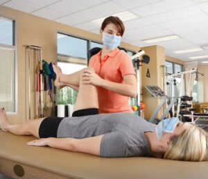 Woman laying on therapy bed after meniscus therapy as therapist bends her knee up during physical therapy.