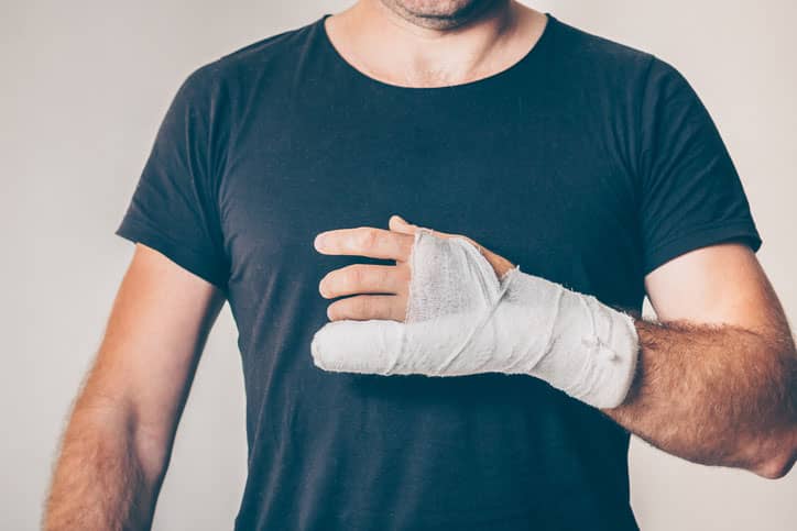 Man in a green shirt holding jammed fingers in a brace.